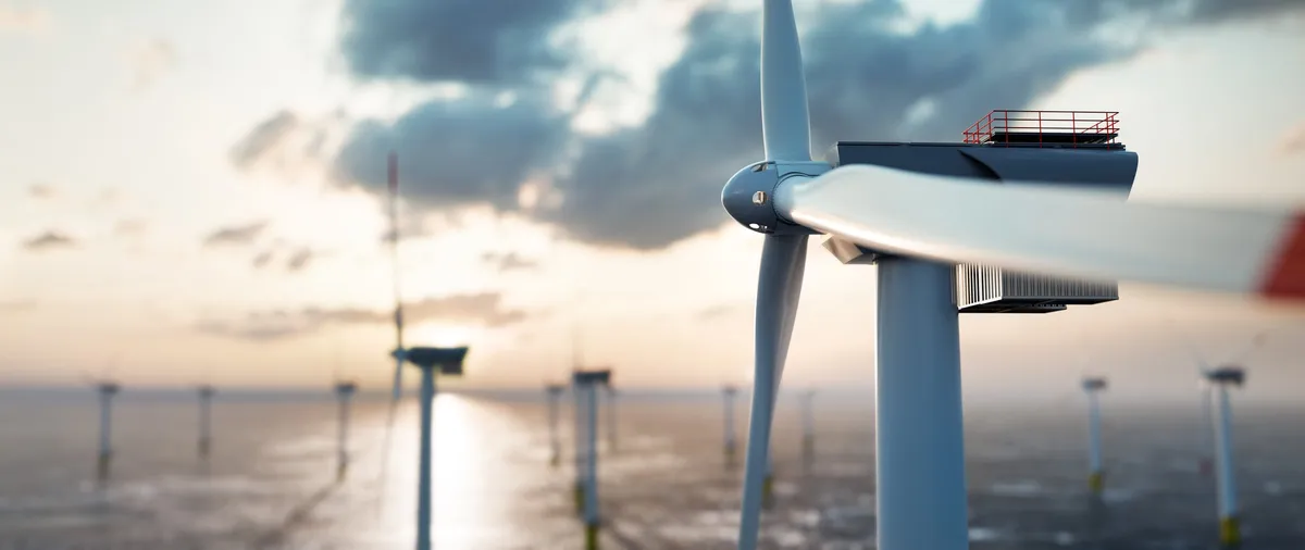 Offshore wind turbines standing in calm water at sunset, one shown close up