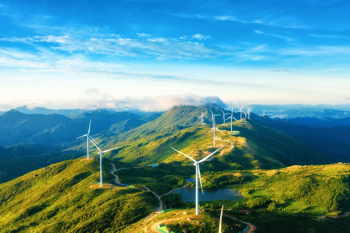 Wind turbines along green mountain ridges under a blue sky
