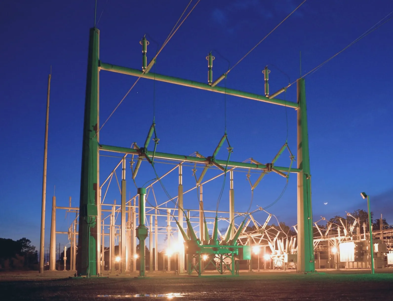 Electrical substation steel structures and floodlights at night under a deep blue sky